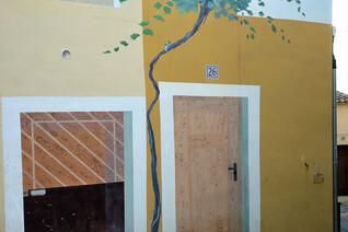 A street art painting in Finestrat depicting a facade of a house and a tree
